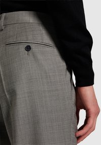 Tailored gray trousers in a textured fabric with a back pocket, featuring a black button and subtle plaid pattern.