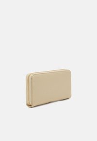 Portafoglio beige con zip, dalla superficie liscia, forma rettangolare e discreti dettagli di cucitura lungo i bordi. Design compatto e minimalista.