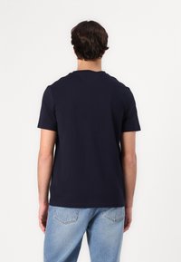 Marineblå bomulds t-shirt med regular fit, korte ærmer og ribbet rund halsudskæring. Ensfarvet bagside uden synlige logoer eller mønstre.
