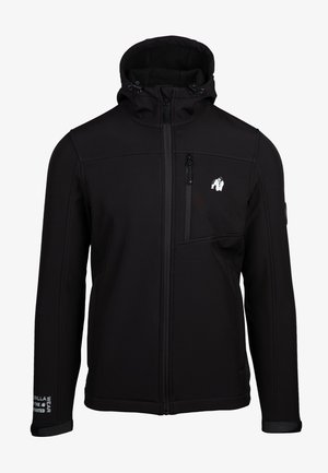 Black softshell jacket with a zipper, adjustable hood, side pockets, and a logo on the chest. Smooth texture, fitted design.
