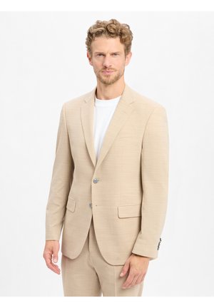 Beige Zweiknopf-Sakko aus einem strukturierten Stoff, mit Reverskragen, zwei Vorderaschen und silberfarbenen Knöpfen. Getragen über einem weißen T-Shirt.