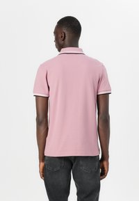 Poloshirt i ljusrosa bomull med svart kant på kragen och ärmarna. Korta ärmar, slim fit-design.