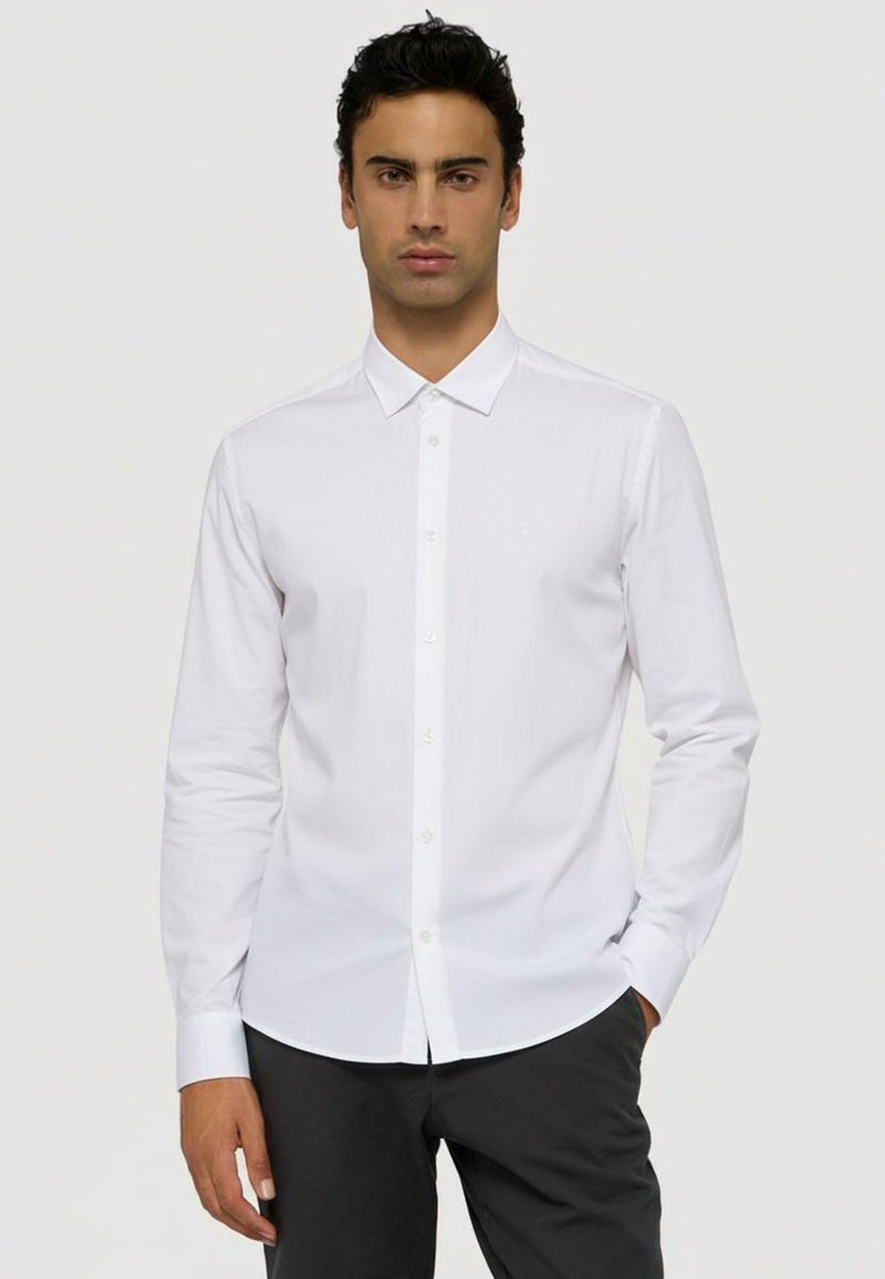 Bílá košile s dlouhým rukávem, špičatým límečkem, zapínáním na knoflíky a slim fit střihem. Vyrobena z hladkého materiálu, s diskrétním logem na hrudi.