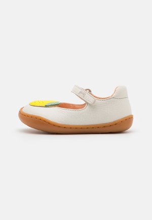 Chaussure pour tout-petit en cuir blanc avec semelle marron, applique fruit jaune à l'avant et fermeture velcro sur fond uni.
