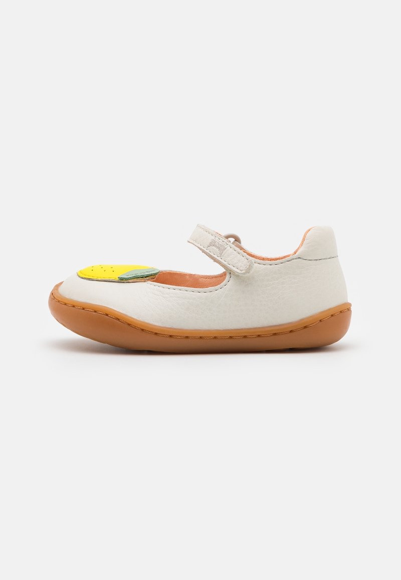 Chaussure pour tout-petit en cuir blanc avec semelle marron, applique fruit jaune à l'avant et fermeture velcro sur fond uni.