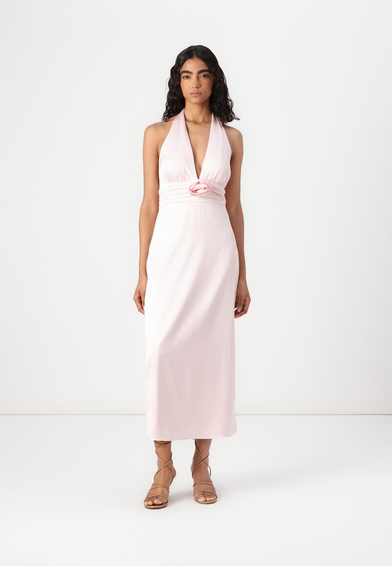 Halter-nack rosa klänning med djup V-ringning, figurnära midja och blommig accent vid midjan. Mjuk tyg med en flödande silhuett.