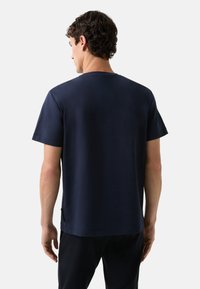 Mørkeblå bomulds t-shirt med korte ærmer, rund halsudskæring og lige kant. Synlig sideslidsdetalje og glat tekstur.