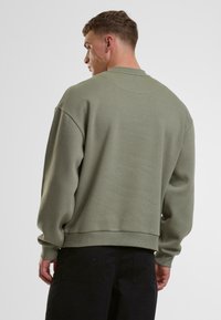 Olivengrøn sweatshirt med afslappet pasform, rund halsudskæring og ribbede manchetter. Blød tekstur, simpel design, ingen synlige mønstre eller hardware.