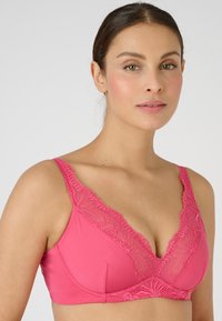 Sujetador de lencería rosa con un escote en V profundo, borde de encaje en los extremos y copas acolchadas suaves para mayor soporte. Tejido suave con un ligero brillo.