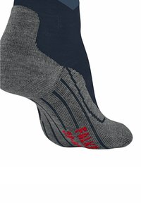 Primo piano di un piede che indossa una calza atletica blu navy e grigia con testo rosso sulla suola e dettagli di ammortizzazione.