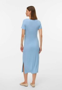 Robe midi côtelée bleu clair avec des manches courtes et des fentes sur les côtés, faite de tissu extensible. Stylisée avec des ballerines beiges et des accessoires minimalistes.