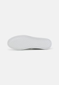 Fehér sneaker talp, textúrált, bordás mintázattal a tapadás érdekében. Kerek orr és sima szélek, tiszta, minimalista dizájnnal.