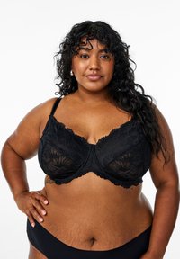 Black lace bra with floral patterns, underwire support, adjustable straps, and scalloped edges. Smooth fabric and sturdy construction.