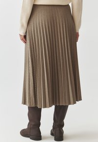 Nabrana midi krila v rjavi houndstooth vzorec, z teksturirano površino. Dopolnjena z rjavimi škornji do kolen.