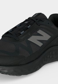 Μαύρο αθλητικό παπούτσι New Balance για τρέξιμο με επάνω μέρος από δίχτυ, μαξιλαρωμένη σόλα και γκρι λογότυπο "N" στο πλάι.