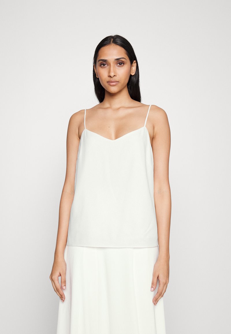Witte top met spaghettibandjes en een V-hals. Glad materiaal, relaxte pasvorm en minimalistisch ontwerp. Combinatie met een vloeiende witte rok.