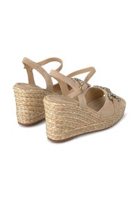 Sandali con zeppa beige, caratterizzati da un tacco in juta texturizzato, con morbidi cinturini in suede e un design a punta chiusa decorato.