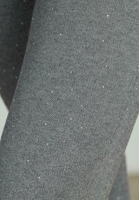 Grijze legging gemaakt van zachte stof met een gestructureerd oppervlak, met kleine metalen spikkels die gelijkmatig verdeeld zijn.