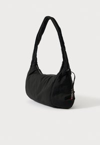 Fekete szövet válltáska ívelt formával, párnázott részletekkel és cipzáras záródással az egyik oldalon. Díszítő hardveres kiemeléssel rendelkezik.