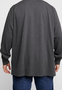 Dark gray long-sleeve shirt with a relaxed fit and round neckline. Soft texture, straight hem, and slightly tapered sleeves.
