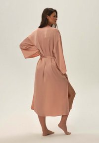 Długa, zwiewna szata z miękkiego różowego satyny, z szerokimi rękawami i paskiem w talii, o luźnym kroju i długości do połowy łydki.