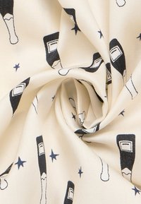 Bomuldsstof med en cremefarvet baggrund, som har et gentaget mønster af sorte og hvide flaskeillustrationer samt små blå stjerner.