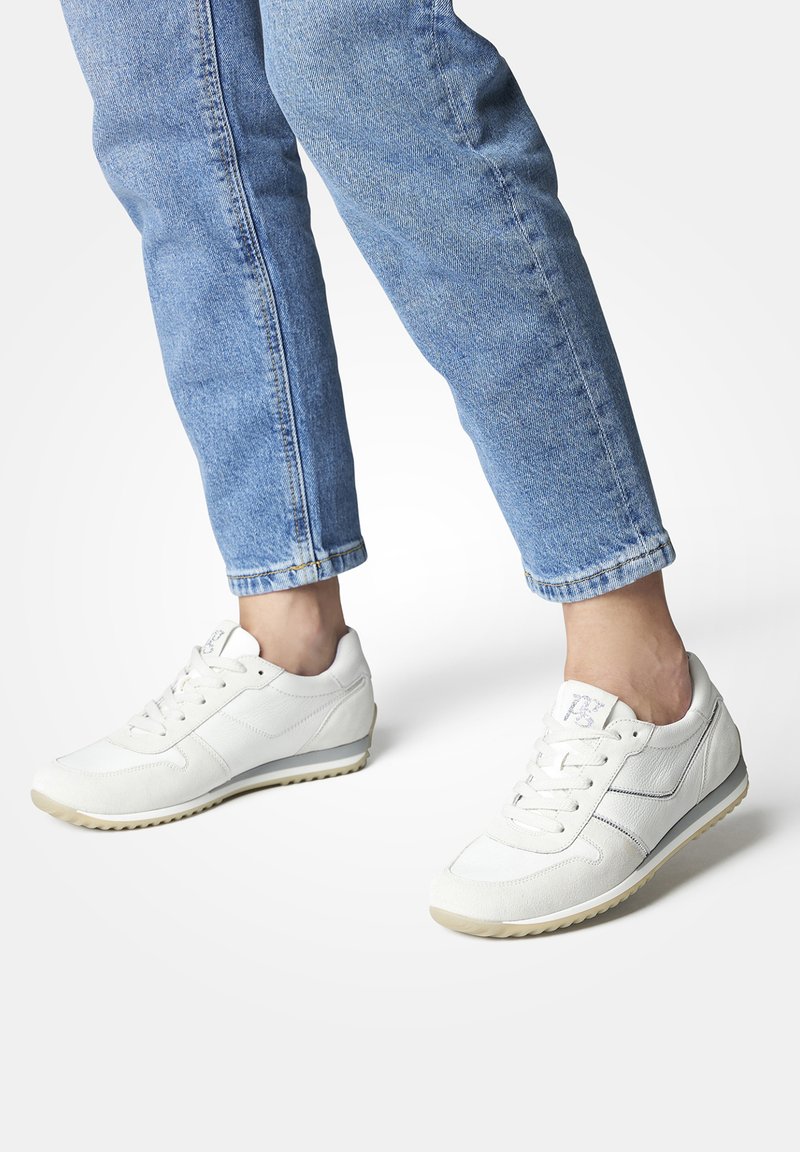 Baskets de sport blanches avec une surface lisse et texturée et des accents gris clair, dotées d'un design à lacets et d'une semelle en caoutchouc segmentée.