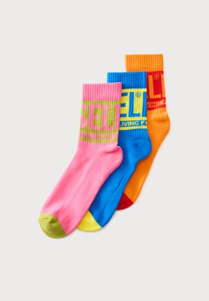 Trois chaussettes montantes colorées en rose, bleu et orange avec des motifs de texte audacieux ; chaque chaussette a des talons et bouts contrastés.