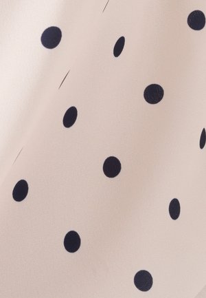 Tela beige claro con textura suave, con lunares grandes de color azul marino distribuidos de manera uniforme por toda la superficie.