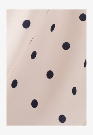 Tela beige claro con textura suave, con lunares grandes de color azul marino distribuidos de manera uniforme por toda la superficie.