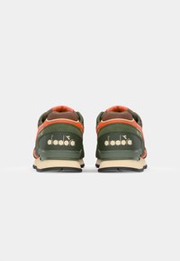 Green and orange athletic shoes with mesh and suede materials, featuring a beige sole and prominent gold branding on the heel.