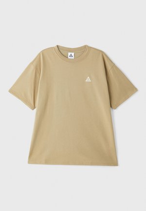 Beige Baumwoll-T-Shirt mit kurzen Ärmeln, Rundhalsausschnitt und einem kleinen, dreieckigen Logo in Weiß auf der linken Brust.