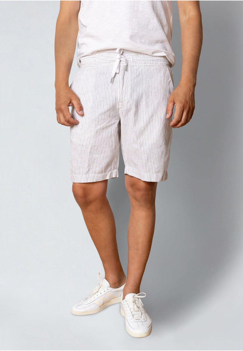 Shorts gris clair rayés avec une taille élastique et un cordon de serrage, offrant une coupe décontractée. Associés à des baskets blanches.