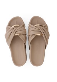 Blote sandalen met een geknoopt ontwerp, een gladde textuur en een gouden cirkelaccent aan de voorkant. Plat voetbed met subtiele branding aan de onderkant.