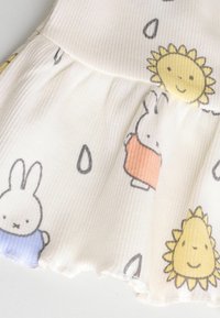 Baumwollkleid mit einem hellen Hintergrund und verspielten Illustrationen von Hasen in Blau-, Orange- und Gelbtönen, die von Sonne-Motiven umgeben sind. Texturiertes, plissiertes Saum.
