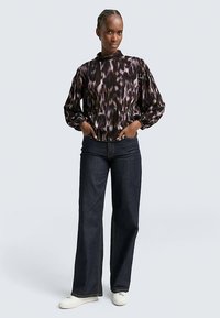 Black and purple patterned blouse with a high neckline, long puff sleeves, paired with dark blue wide-leg jeans and white sneakers.