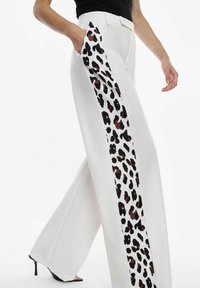 Pantaloni bianchi a gamba larga con pannello laterale in stampa leopardata marrone e nera. Tessuto morbido con una vestibilità sartoriale e una tasca laterale.