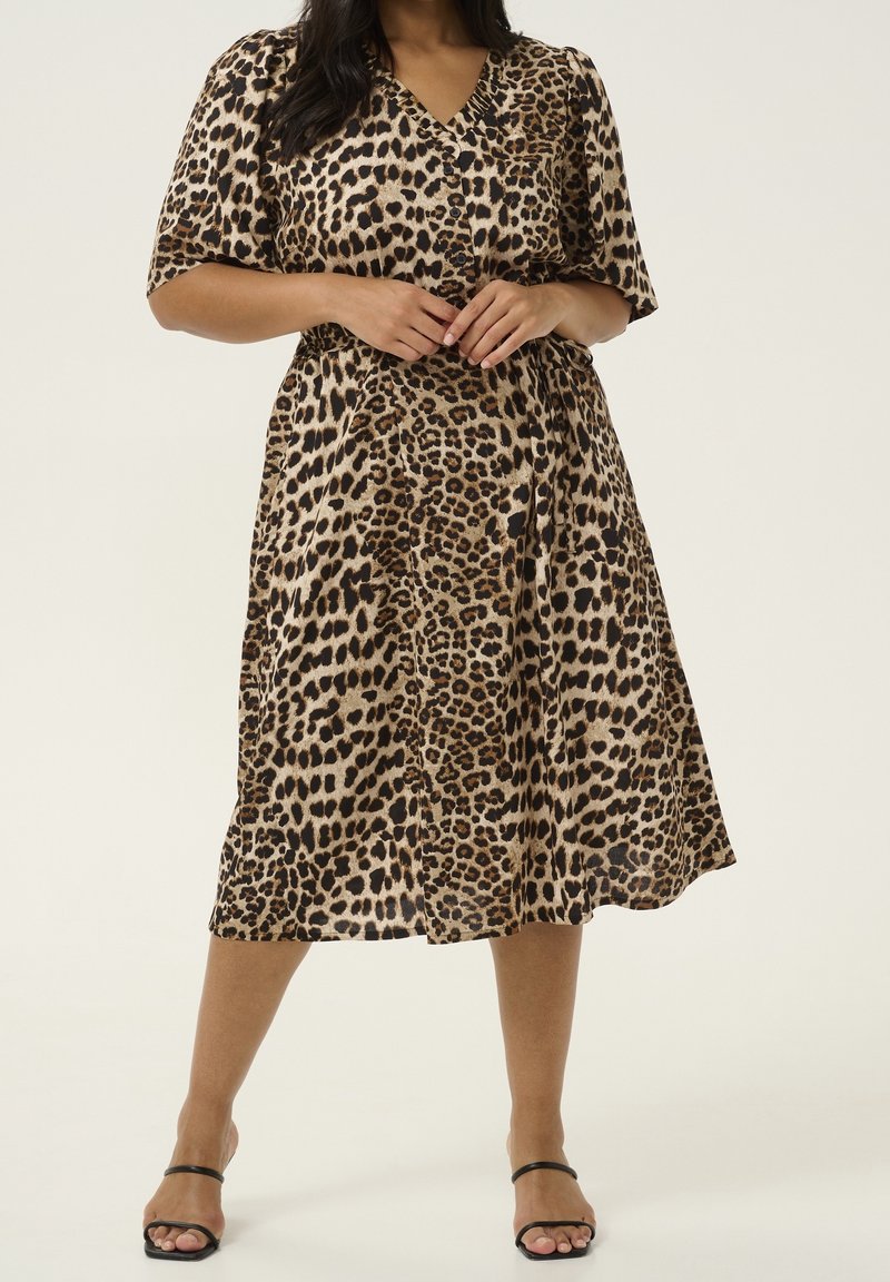 Kleid mit Leopardenmuster, V-Ausschnitt, kurzen Ärmeln und tailliertem Bund. Hergestellt aus leichtem Stoff, verfügt es über einen knielangen Rock und Knöpfe.