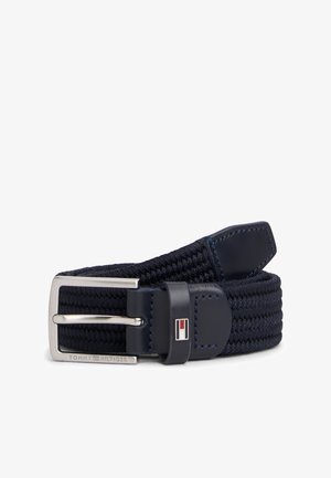 Granatowy pasek z tkaniny o splocie z prostokątną srebrną klamrą i skórzanymi elementami, z małym logo w kolorach czerwonym, białym i niebieskim.