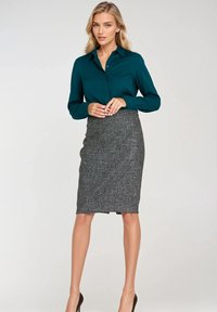 Turbia bluzka z kołnierzykiem i długimi rękawami w połączeniu z szarym, teksturowanym ołówkowym spódnicą. Całość dopełniają szpilki.