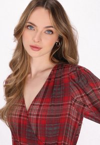 Rood geruite blouse met pofmouwen, een diepe V-hals en een lichte stof met intrigerende patronen van zwart en grijs accenten.