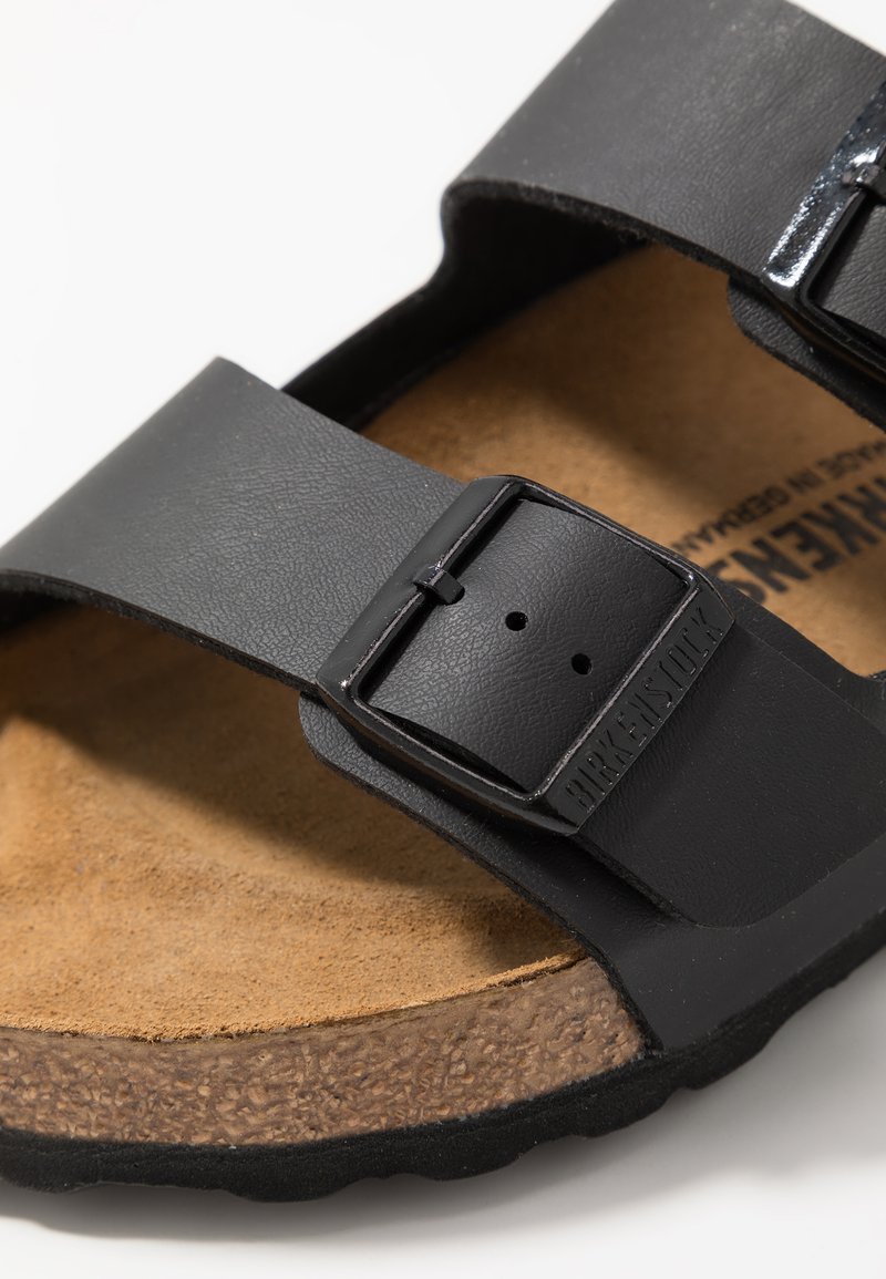 Black leather sandal with two adjustable straps, a cork footbed, and a textured rubber sole. Features metal buckles for secure fit.