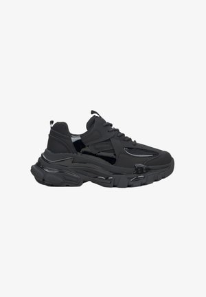 Zwarte sneaker met een dikke zool. Beschikt over een mix van matte en glanzende texturen, mesh-panelen en een gevoerde tong voor comfort.
