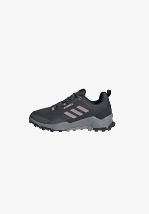 Zwarte sportieve schoen met een bovenwerk van mesh, grijze rubberen zool en drie lichtgrijze strepen. Heeft een versterkte neus en een gestructureerd ontwerp.