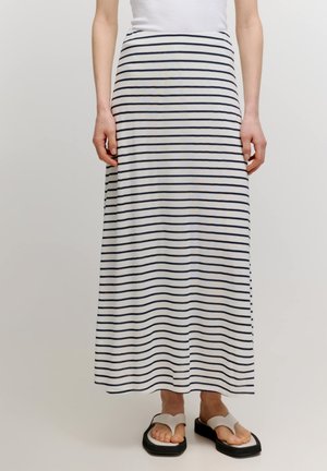 Gestreiftes Maxikleid aus leichtem Stoff, mit einem weißen Grund und dunkelblauen horizontalen Streifen. Kombiniert mit weißen und schwarzen Flip-Flops.