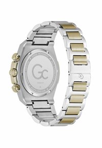 Ceas din inox cu brățară argintie și aurie, carcasă pătrată și dublă coroană, având un finisaj lustruit și zale netede.