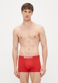 Boxer rossi realizzati in morbido cotone con un elastico in vita brandizzato, caratterizzati da un design aderente e una texture liscia.