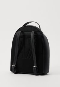 Mochila negra hecha de cuero texturizado y malla, con correas ajustables, parte superior redondeada y un detalle de logo prominente.