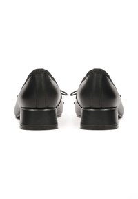 O pereche de pantofi oxford din piele neagră, cu tocuri joase, prezentată din spate pe un fundal alb.