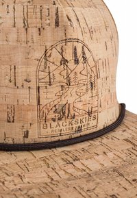 Cork hat with a wide brim, featuring an embossed logo and nature design. Smooth texture with a light brown color and dark accents.